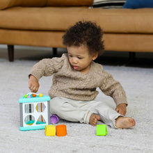 Baby playing with teal and white activity triangle shape sorter on the floor