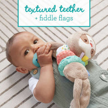 Baby playing with plush sloth toy showing colorful rings and teal teether