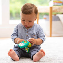 Baby sitting and holding a teal music-light key teether with red textured ring