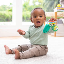 Baby holding a teal music-light key teether with red textured ring