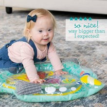 Baby using a teal narwhal-shaped play mat with floating sea animal characters