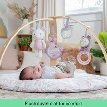 Baby activity gym with wooden arch and plush hanging toys over round quilted play mat