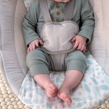 Infant in cushioned portable swing with matching leaf-pattern seat pad