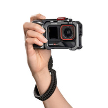 Hand holding an action camera showing the front lens and display