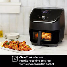 Black air fryer on countertop with basket door window and roasted food