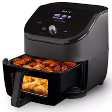 Black air fryer with open basket and cooking tray, fries visible through the front window.