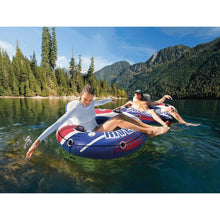 Inflatable river float carrying two riders on a lake, red-and-blue RiverRun design