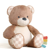 Brown plush bear with white belly, checkered paws, and ribbon tags at side