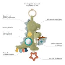 Olive green dino toy with teal ring, crinkle spikes, ribbon strips, and orange star clip