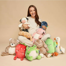 Green cactus plush with smiling face and multicolor sensory ribbon details in a toy pile