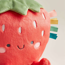 Close-up plush strawberry with red fabric, green leaf, stitched smiling face and ribbon tabs