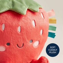 Close-up plush strawberry with red fabric, green leaf, stitched face, and ribbon tabs
