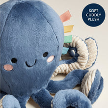 Blue plush octopus close-up with embroidered eyes and textured ribbon tail.