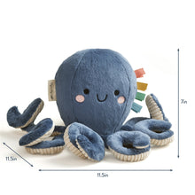 Blue plush octopus with smiling face, textured tentacles, and soft dangling ribbon accents.