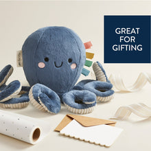 Blue plush octopus with smiling face, corded tentacles, and dangling ribbon loops.