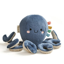Blue plush octopus with smiling stitched face, soft tentacles, and multicolor ribbon tags.