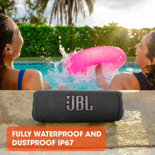 Black JBL Flip 6 portable speaker on a pool ledge with water splashing around it.