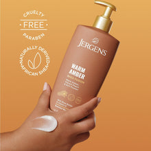 Jergens Warm Amber body lotion bottle with gold pump, held in hand with lotion