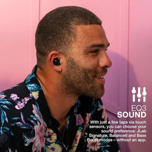 Black true wireless earbuds in use on a man’s ear, earpieces visible
