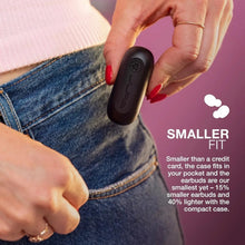 Black charging case with compact earbuds, held near blue denim jeans