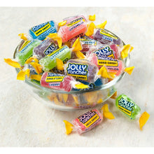 Assorted fruit flavored hard candy pieces in a glass bowl with several wrapped candies