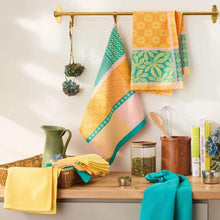 Colorful jacquard kitchen towels hanging on a wooden bar above a counter