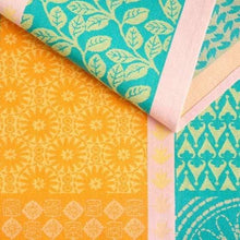 Jacquard kitchen towel fabric close-up, teal leaves over orange daisy pattern