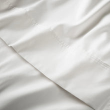 White fitted sheet fabric close-up with smooth weave and stitched edge