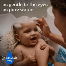 Baby with shampoo foam being rinsed by a caregiver’s hands