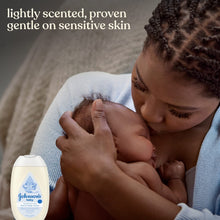 Johnson's baby sensitive face & body cream bottle next to parent holding a baby