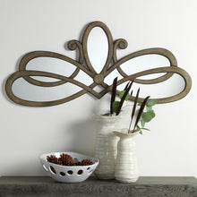 Ornate wall mirror with bronze-toned scroll frame and oval reflective center