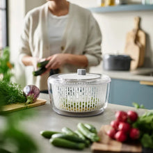 Transparent salad preparation chopper bowl on countertop with vegetables