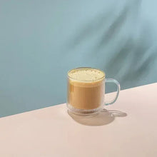 Fluted double-wall glass mug with amber coffee and foamy top, clear handle