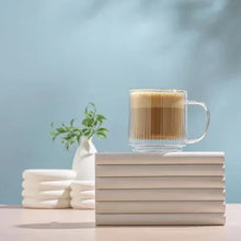 Fluted double-wall glass mug with amber coffee and froth, handle visible