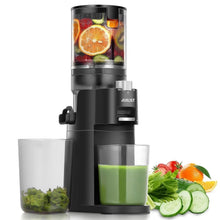 Black slow masticating juicer dispensing green juice into cups with fruits and herbs.