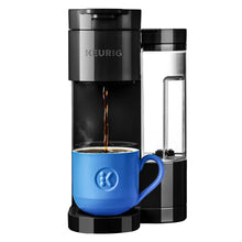 Black single-serve coffee maker with coffee streaming into a blue mug