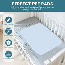 Light blue bed pad lying flat on a gray mattress near a white crib rail