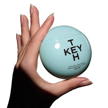 KEYTH perfumed hand cream tin in teal, shown in a hand
