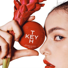 KEYTH perfumed hand cream tin in red, held near face and bouquet