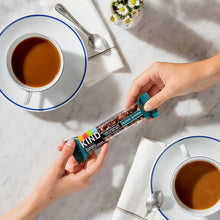 Hand holding KIND snack bar, dark chocolate nuts & sea salt, in teal wrapper.