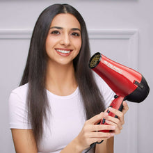 Red and black hair dryer with concentrator attachment held near dark hair