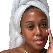 White gel-cream applied on face, hair wrapped in a towel