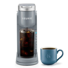 Gray iced coffee maker with tall iced coffee glass and blue mug