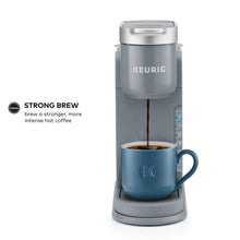 Gray single-serve coffee maker pouring into blue mug, with strength controls