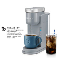 Gray single-serve coffee maker with blue mug and glass of iced coffee