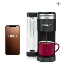 Single-serve pod coffee maker with red mug; smartphone shows the Keurig app