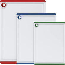 Three large plastic cutting boards with multicolor edges, hole handles and juice grooves
