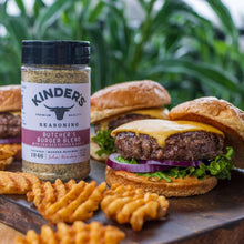 Seasoning bottle with black cap beside burger with melted cheese and fries