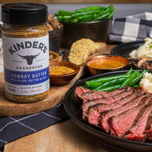 Seasoning bottle with cowboy butter label beside grilled meats and asparagus
