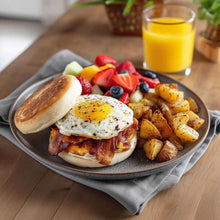 Seasoning over breakfast plate with fried eggs, bacon, and roasted potatoes